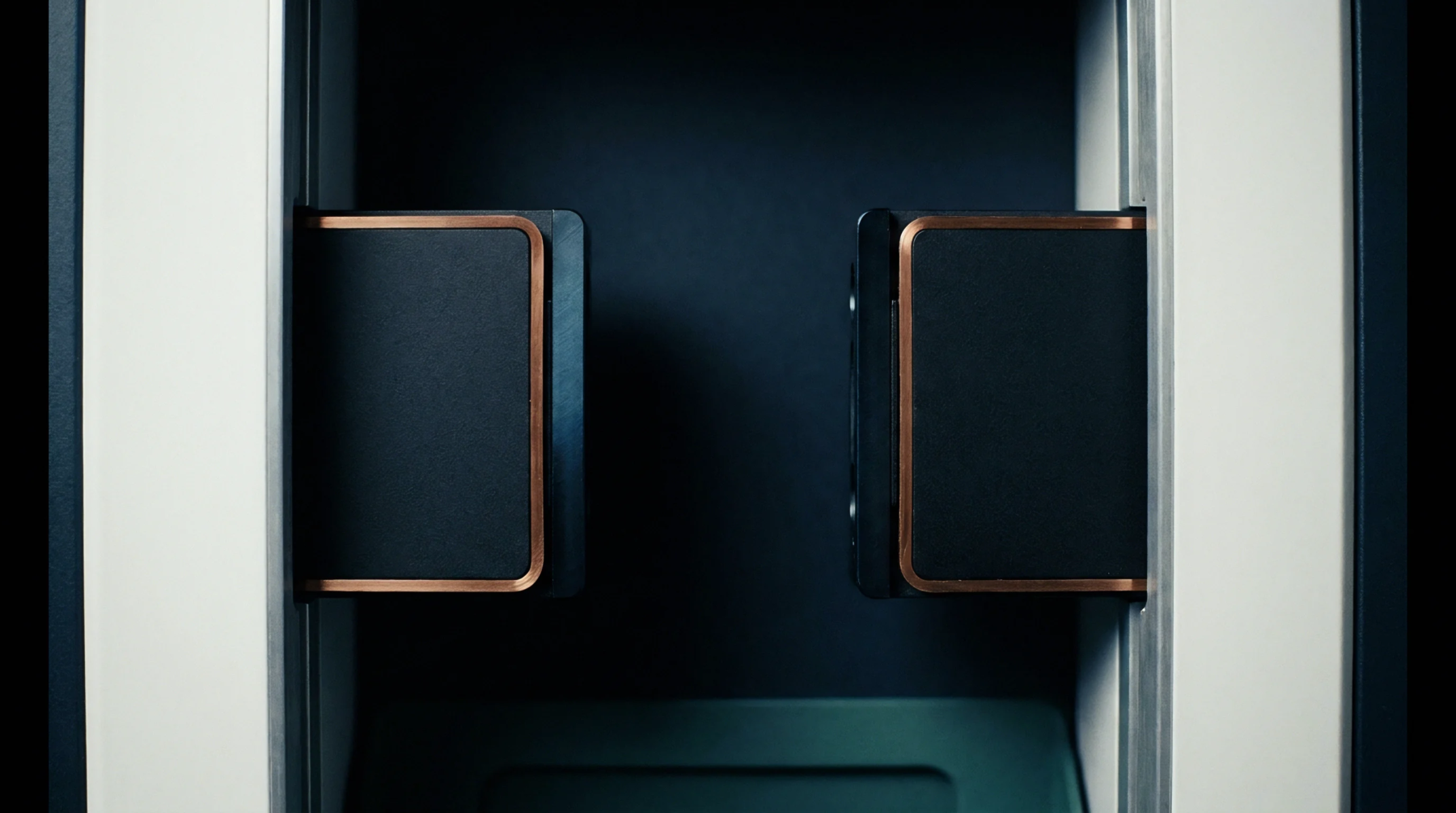 Two rectangular sensor modules with copper edges are mounted symmetrically on vertical aluminum rails within a dark matte enclosure for automated inspection.